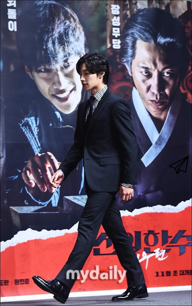 Walking in front of the movie 'The Hand of God' poster