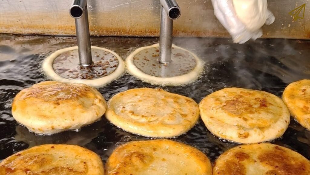 Photo of hotteok being fried in oil on a hot iron plate