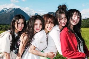 kiiikiii members are hugging each other in a natural setting and sticking their tongues out