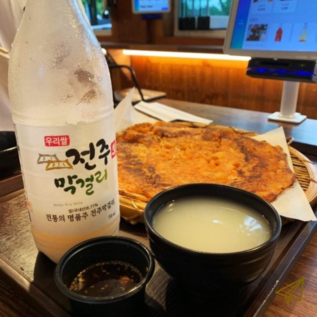 On the table are bowls filled with pajeon and makgeolli.