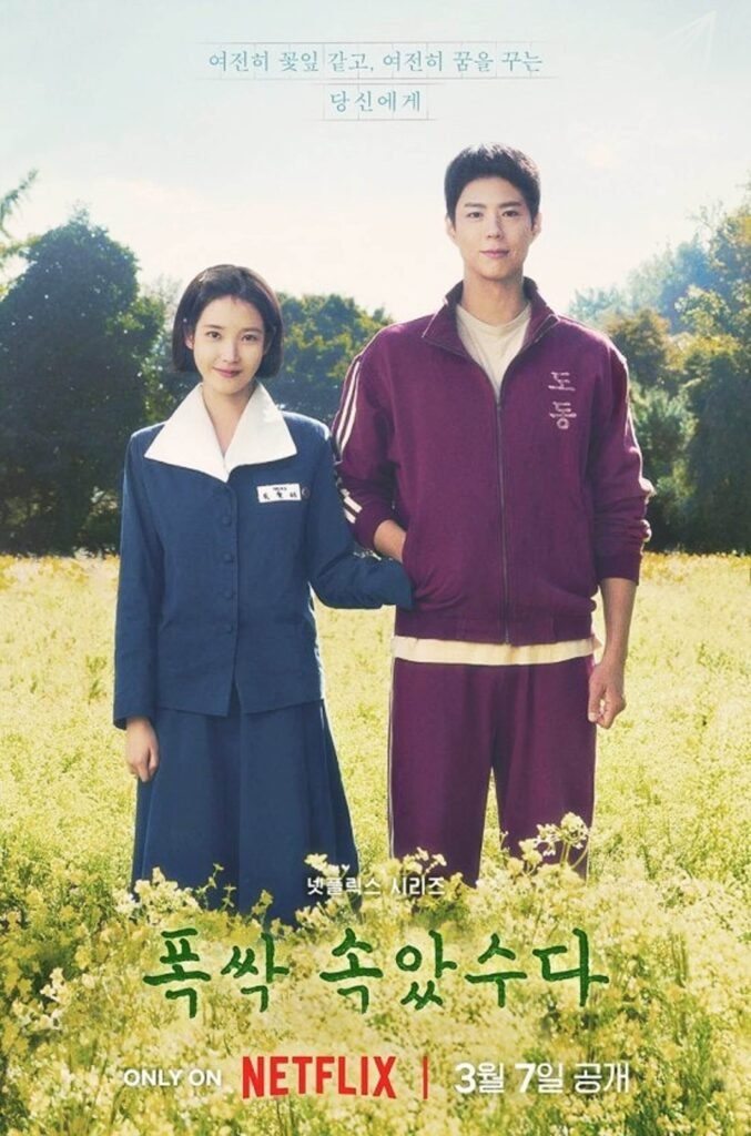 IU and Park Bo-gum standing in a field of rapeseed flowers