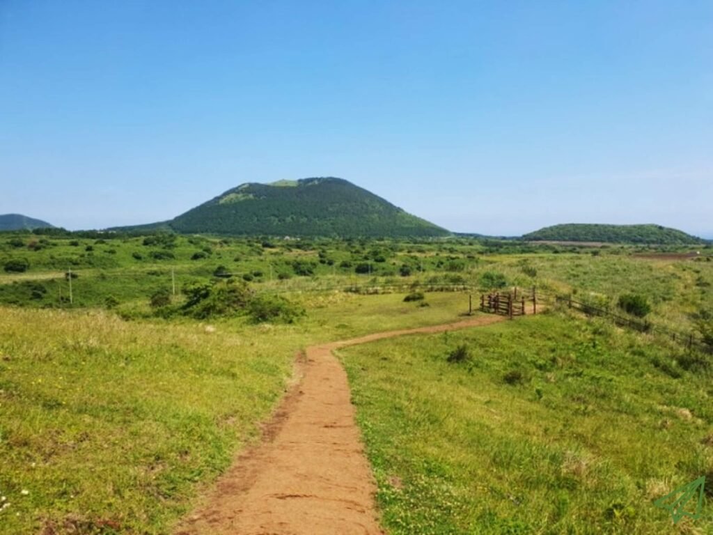 There is a path on the top of Yongnuni Oreum, and many mountains are spread out in the distance.
